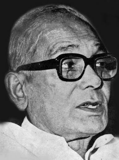 High-contrast close portrait of Jaya Prakash Narayan in heavy black-framed spectacles, speaking