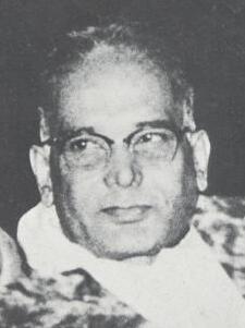 Small, grainy black and white photographic detail showing the head and shoulders of a man in spectacles